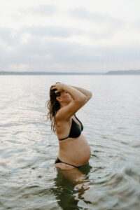 Austin Maternity Photographer, Pregnant woman in bathing suit standing in lake