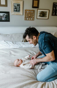 father playing with newborn photo