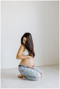 Mother kneels down holding belly for Austin Motherhood Photographer