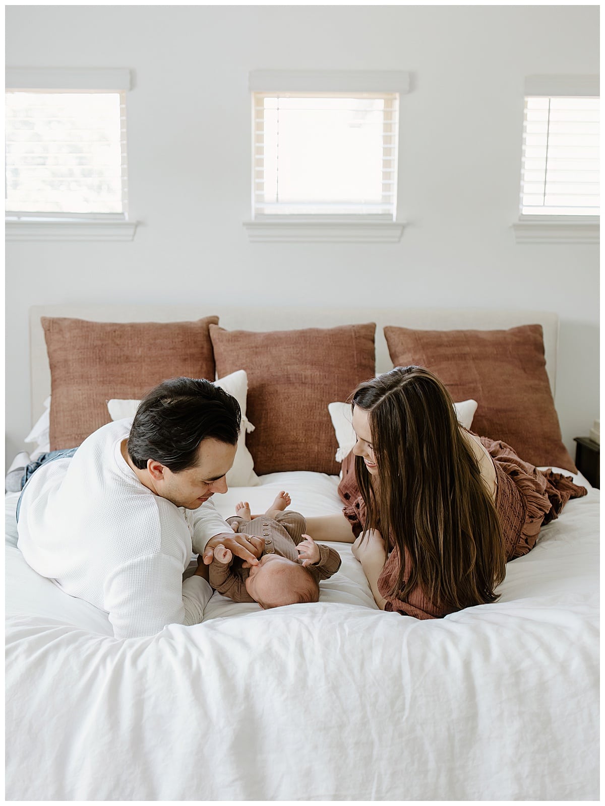 Mom and dad smile at baby on the bed for Austin Newborn Photographer