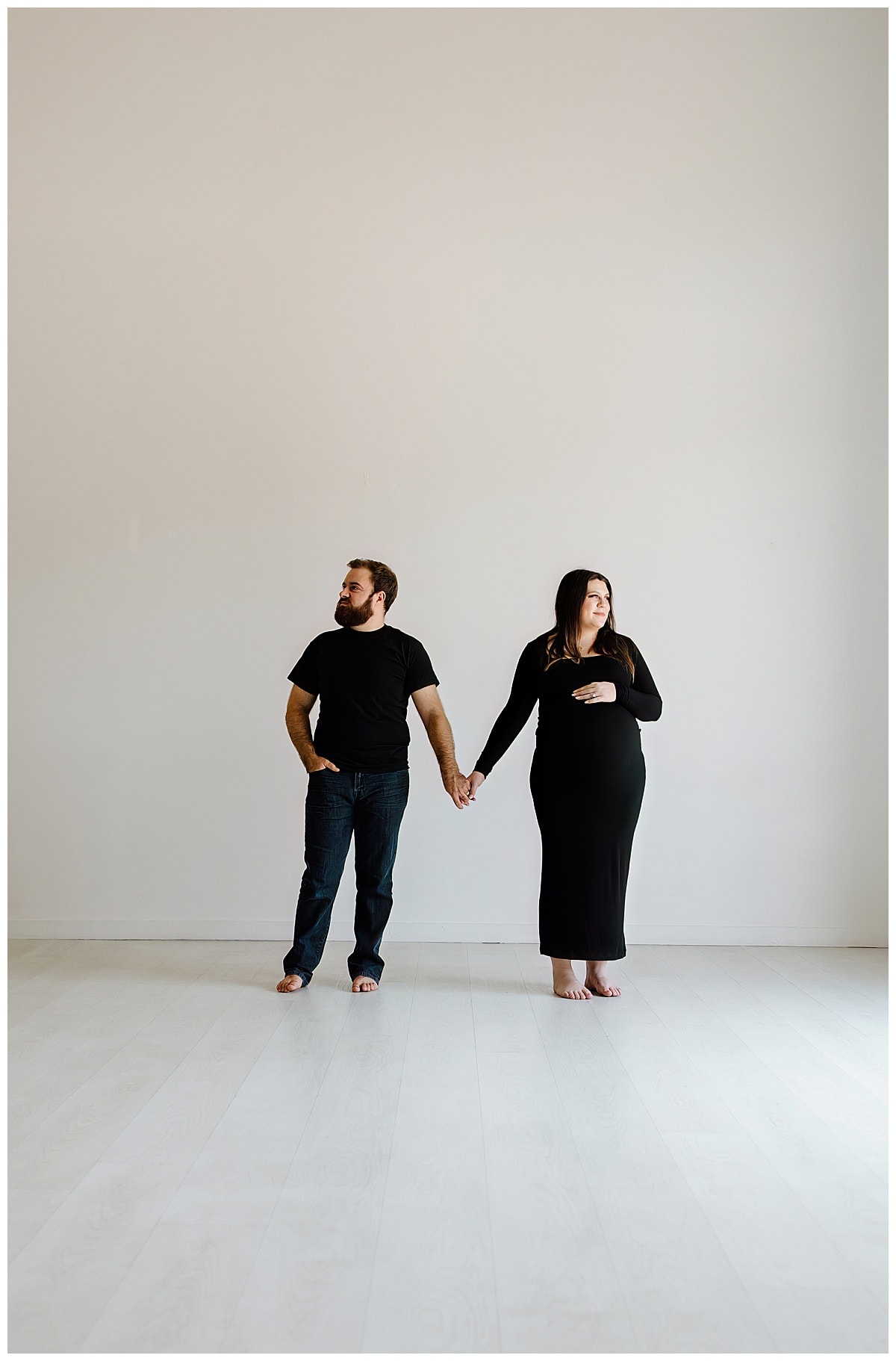 Couple holds hands together during her studio maternity session