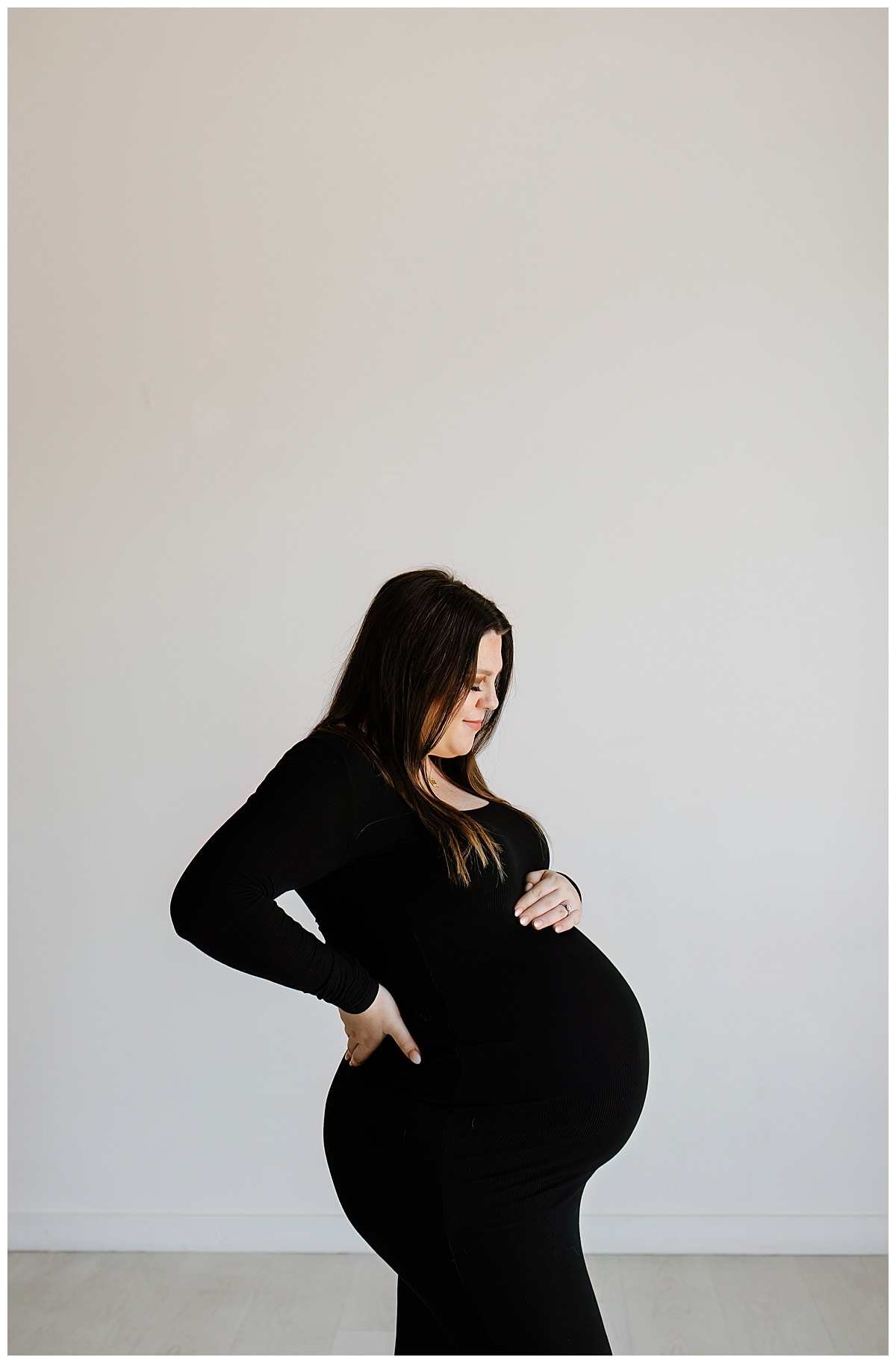 Woman smiles at baby bump during her studio maternity session