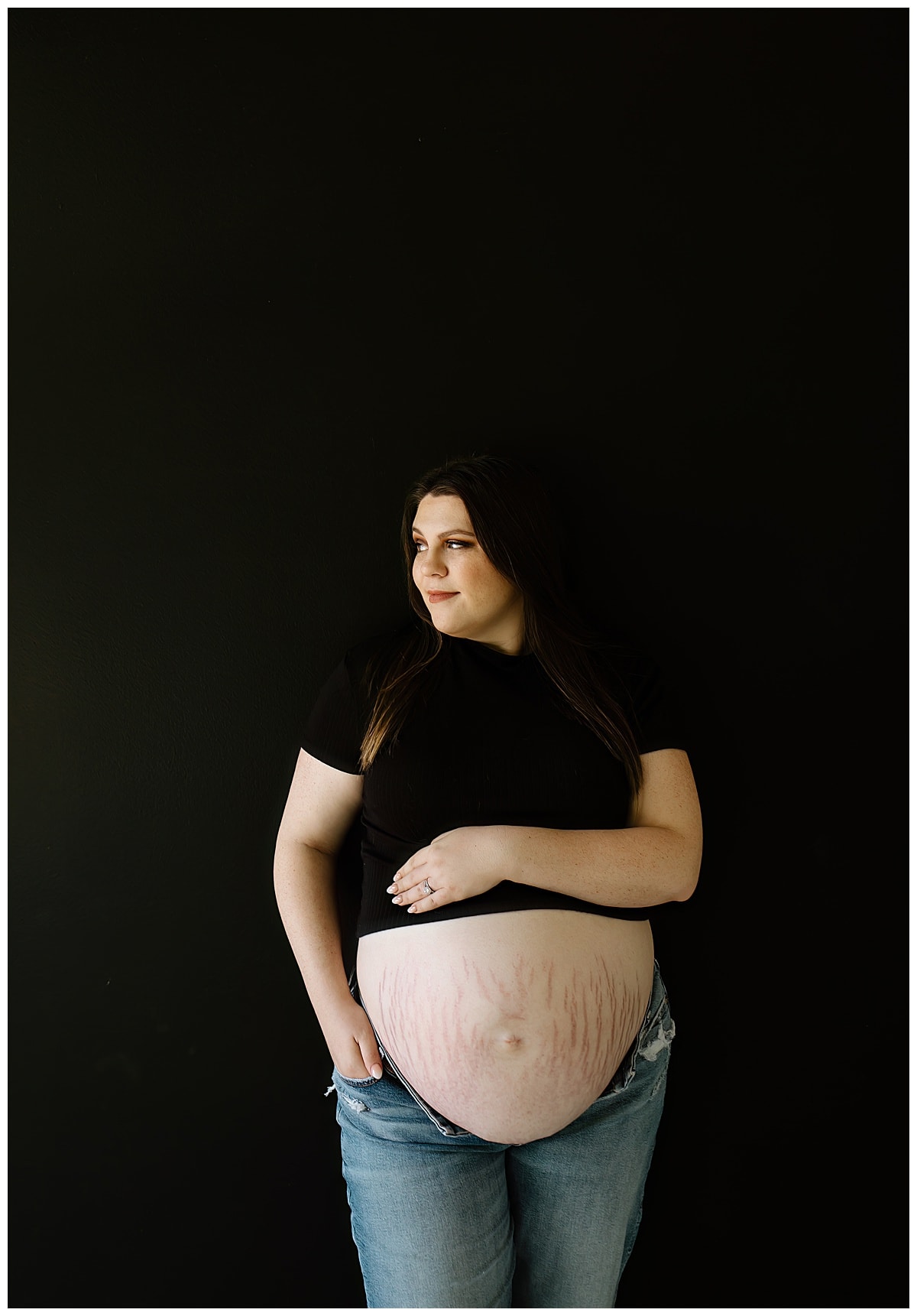 Mama holds pregnant belly during her studio maternity session