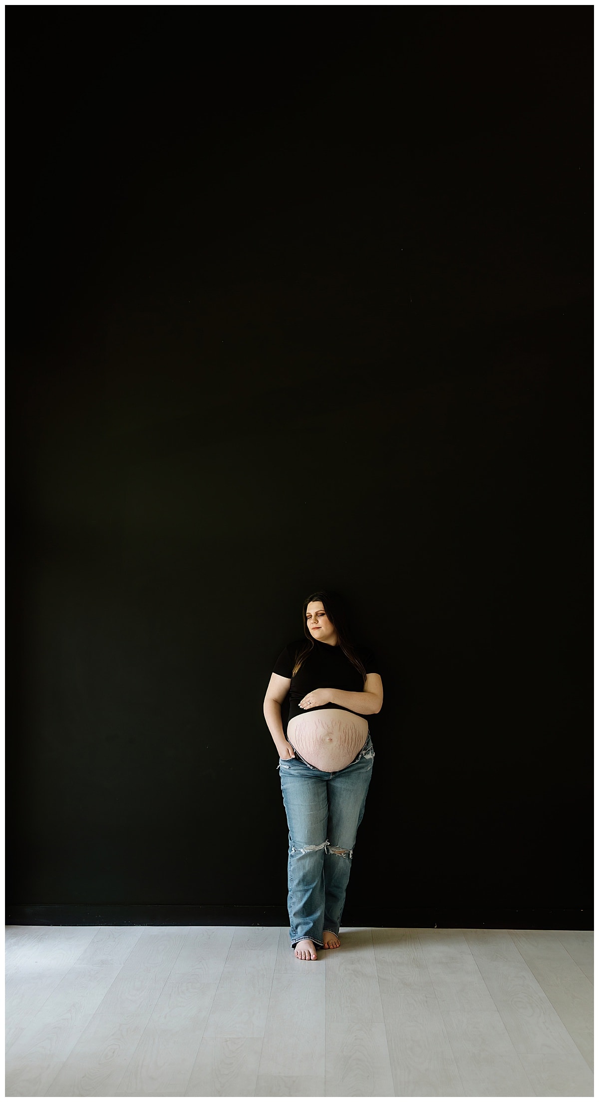 Woman holds pregnant belly during her studio maternity session