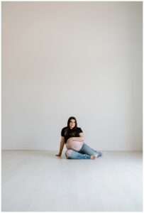 Adult lays on the floor holding her belly for her studio maternity session
