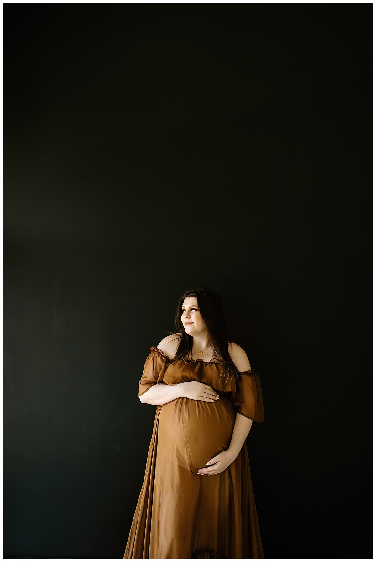 Mama grabs belly during her studio maternity session