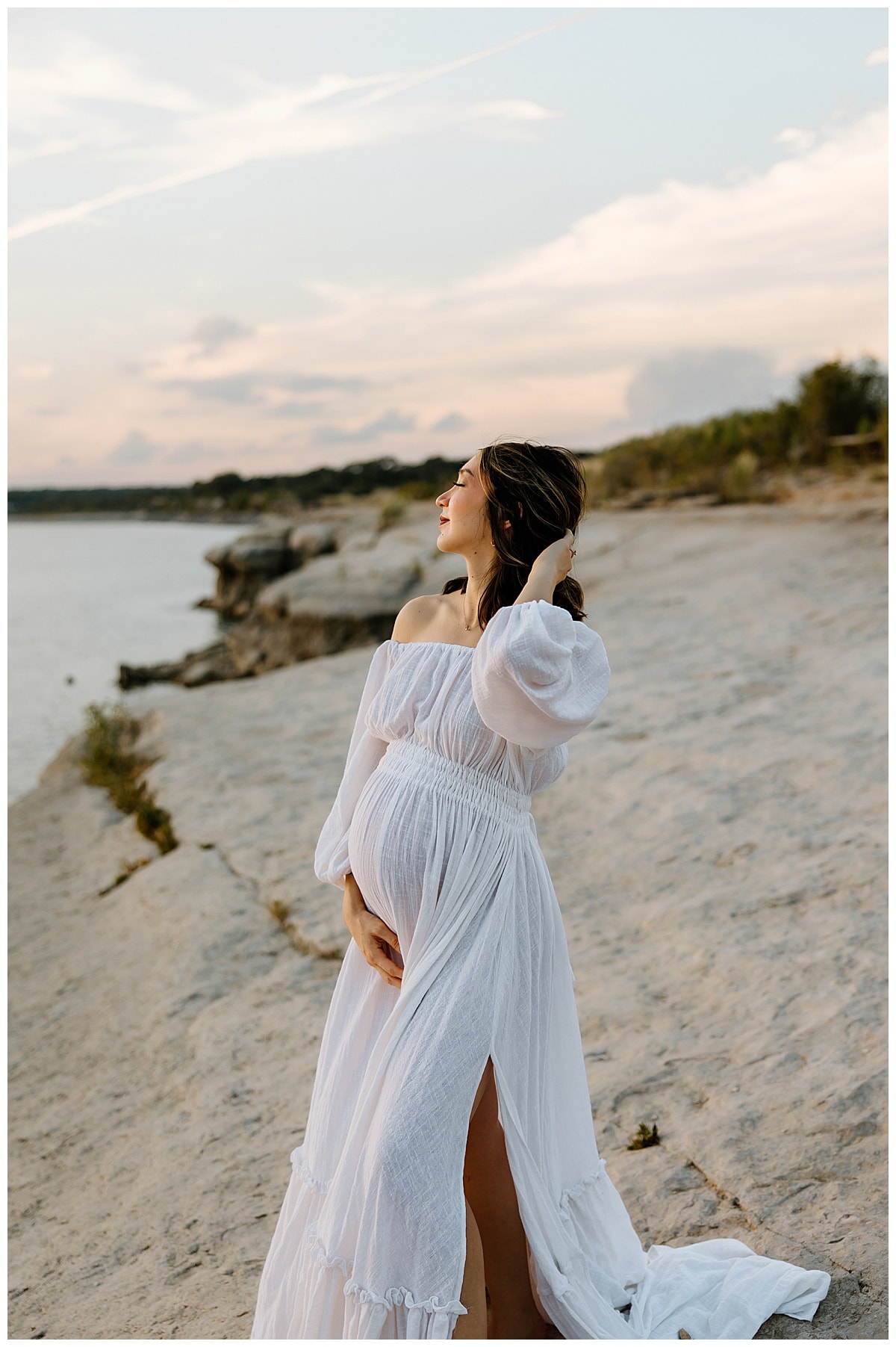Woman holds hands behind her head during her outdoor maternity session