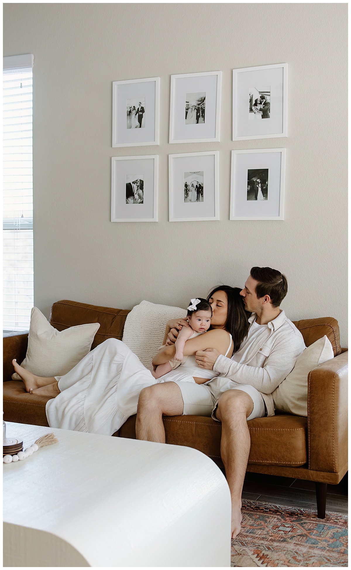Mom and da sit together on the couch with their baby for Austin Motherhood Photographer