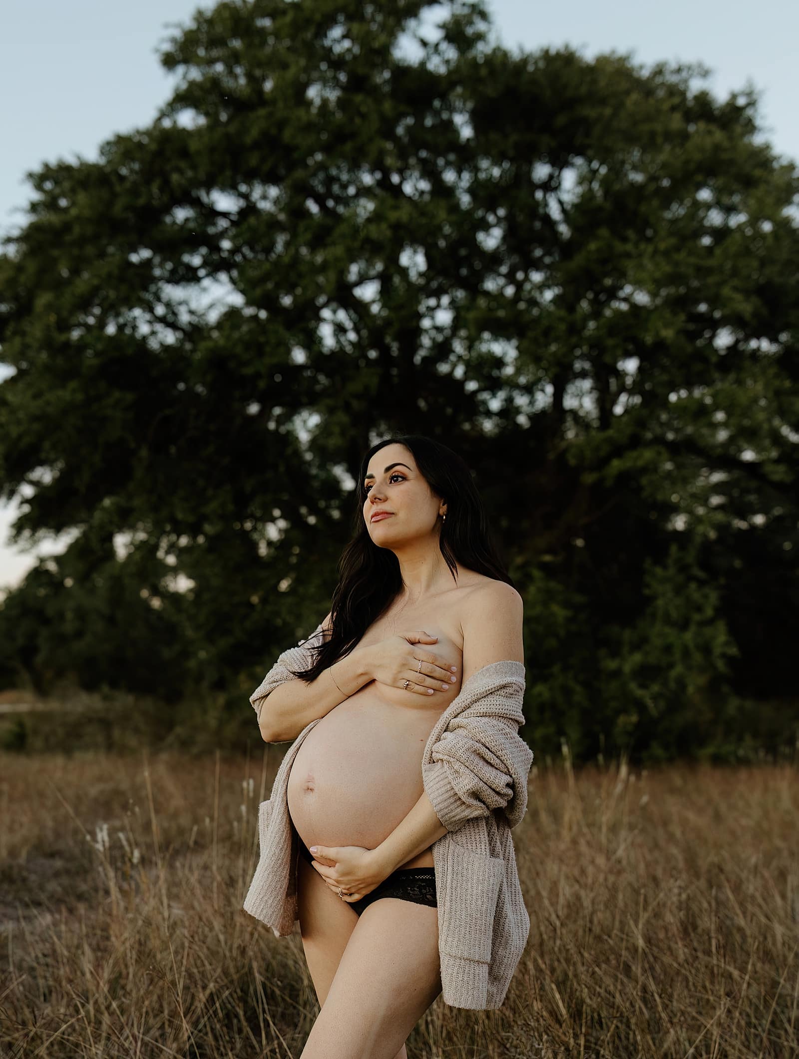 Mom covers chest and holds pregnant belly for Our Adventuring Souls Photography