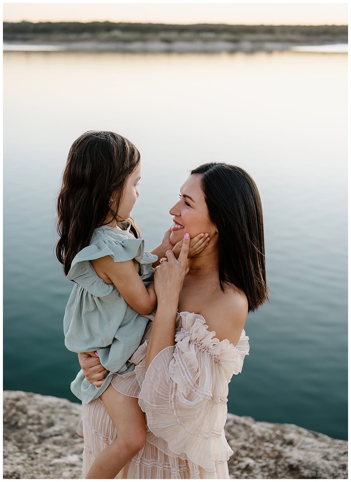 Mom and daughter smile at each other during their outdoor lifestyle photoshoot