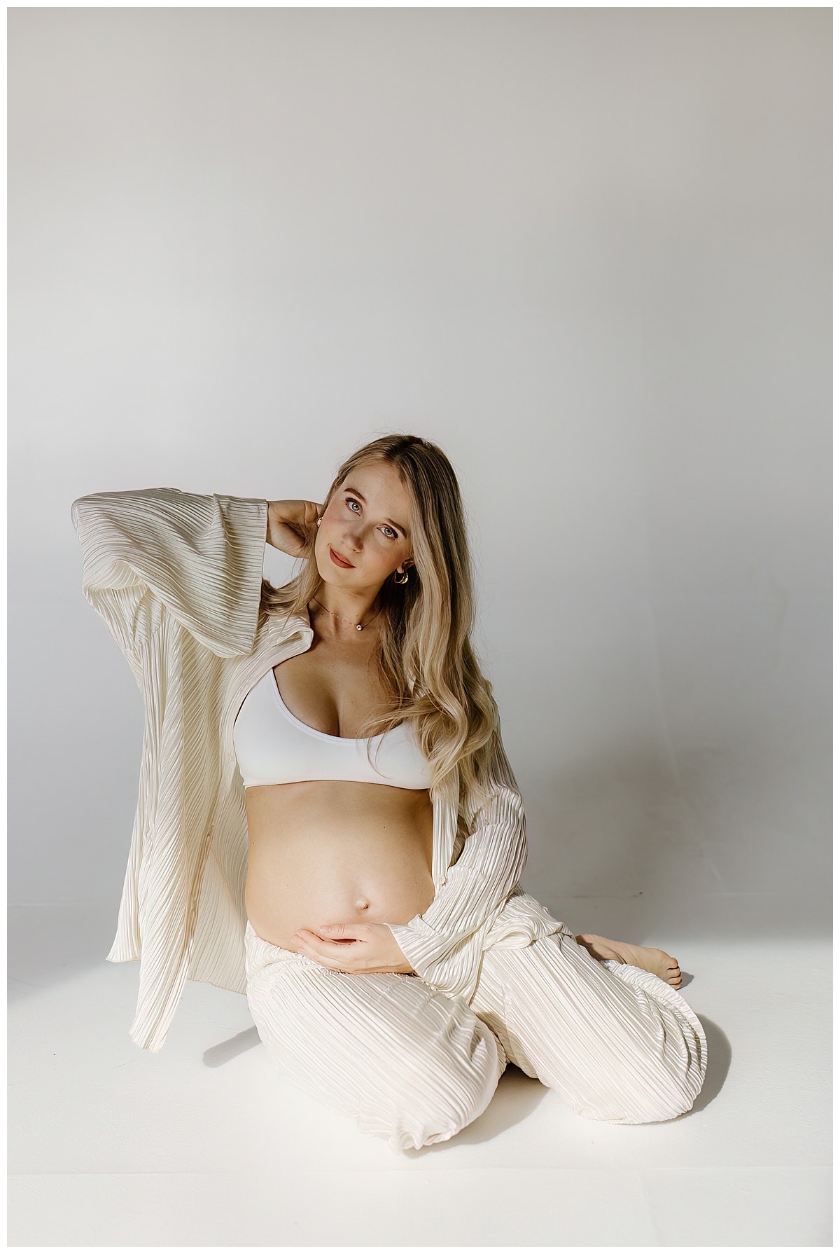 Woman grabs her pregnant belly during her studio maternity session