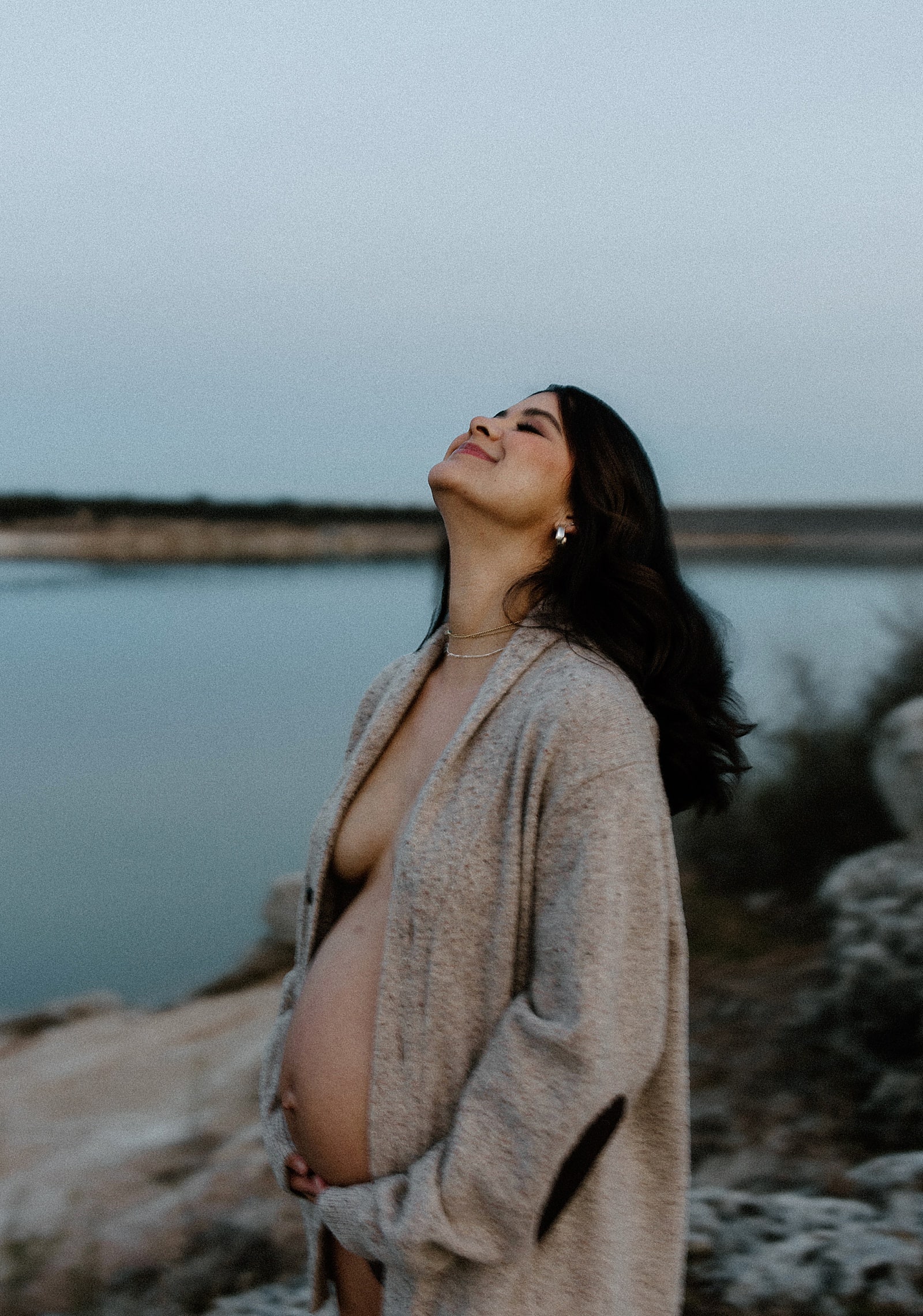 Woman smiles holding her baby bump for Our Adventuring Souls Photography